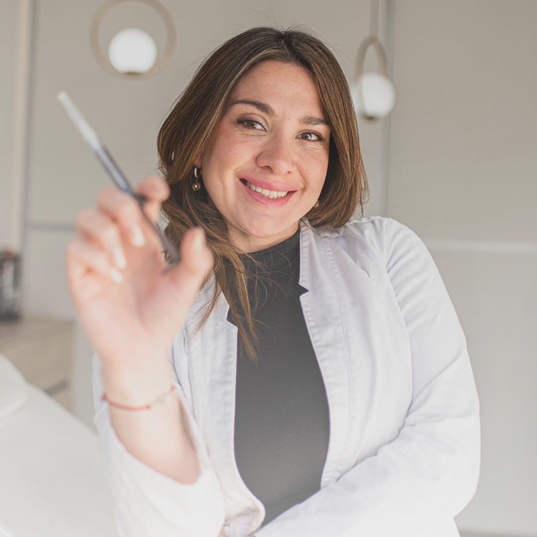 La Dra. Luisina Moyano, con guardapolvo blanco, sonríe en su consultorio